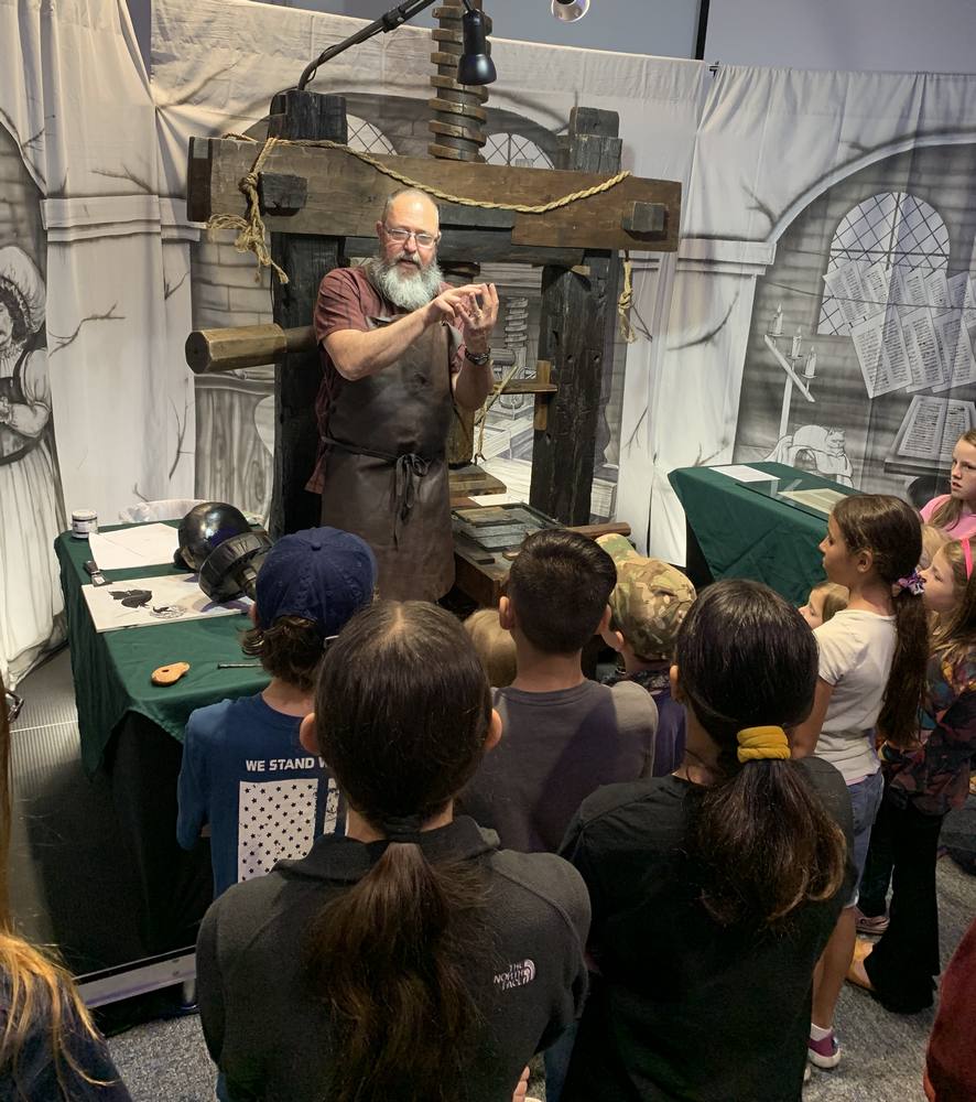 John Sliffe doing a printing press presentation to a group of kids